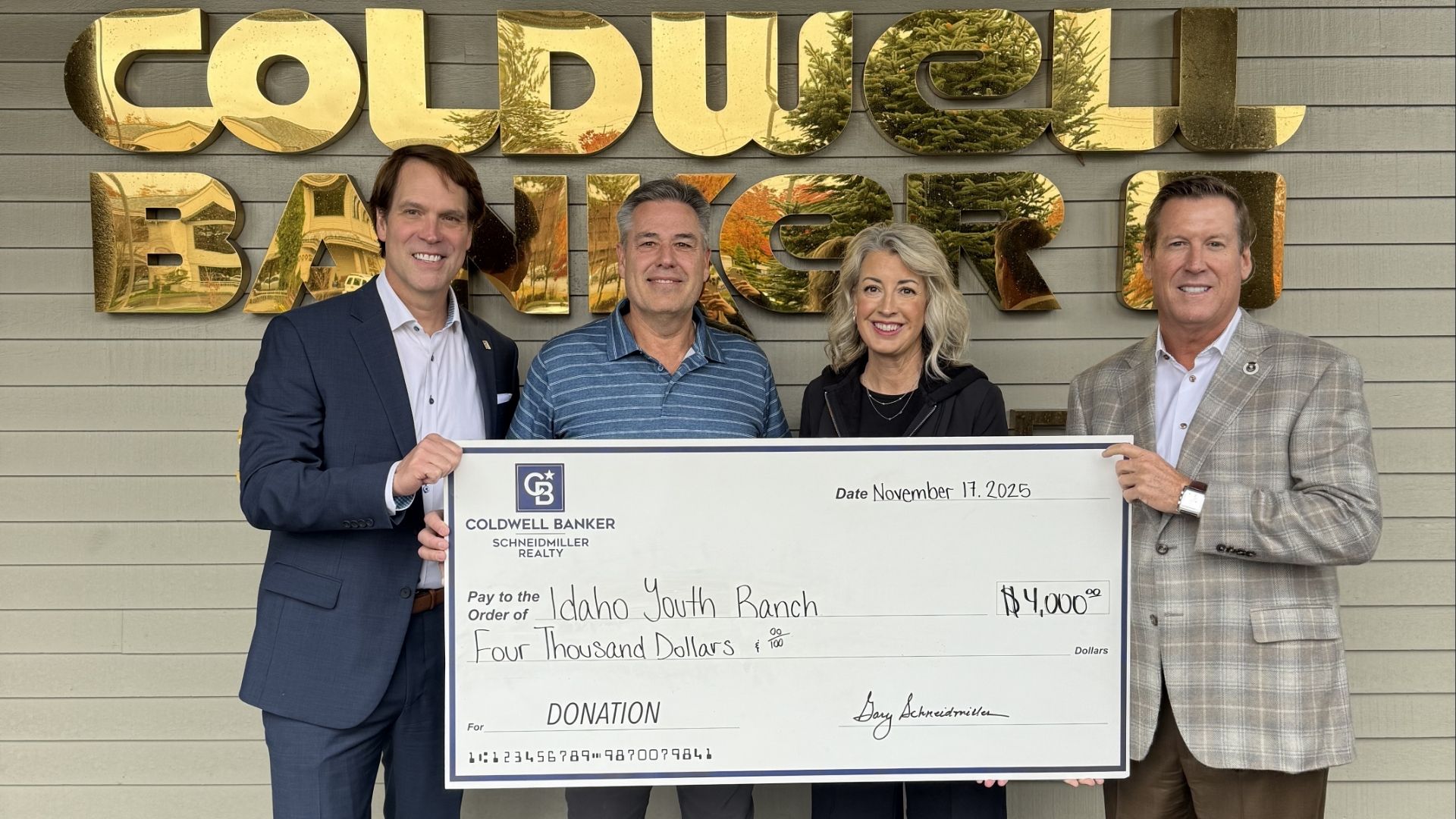 Schneidmiller Realty leadership holding a large donation check for Idaho Youth Ranch
